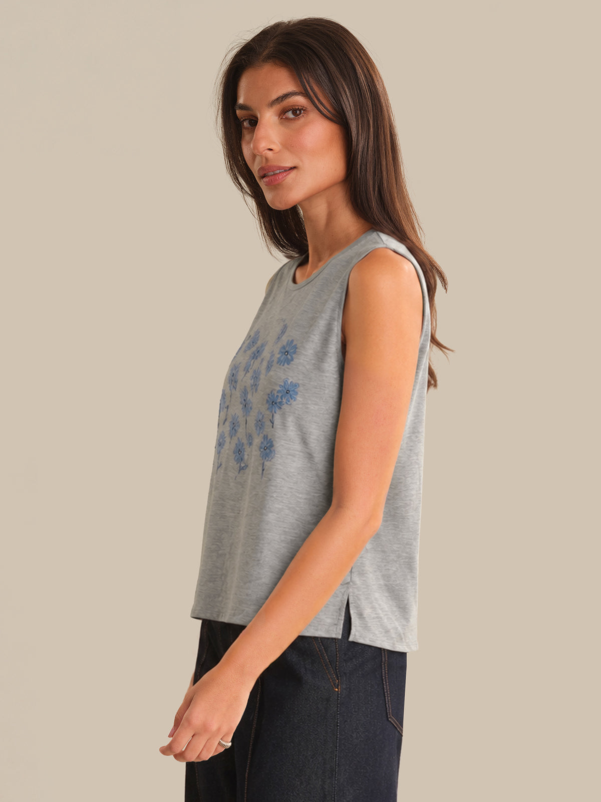 Woman wearing a gray sleeveless top with blue floral patterns on a beige background