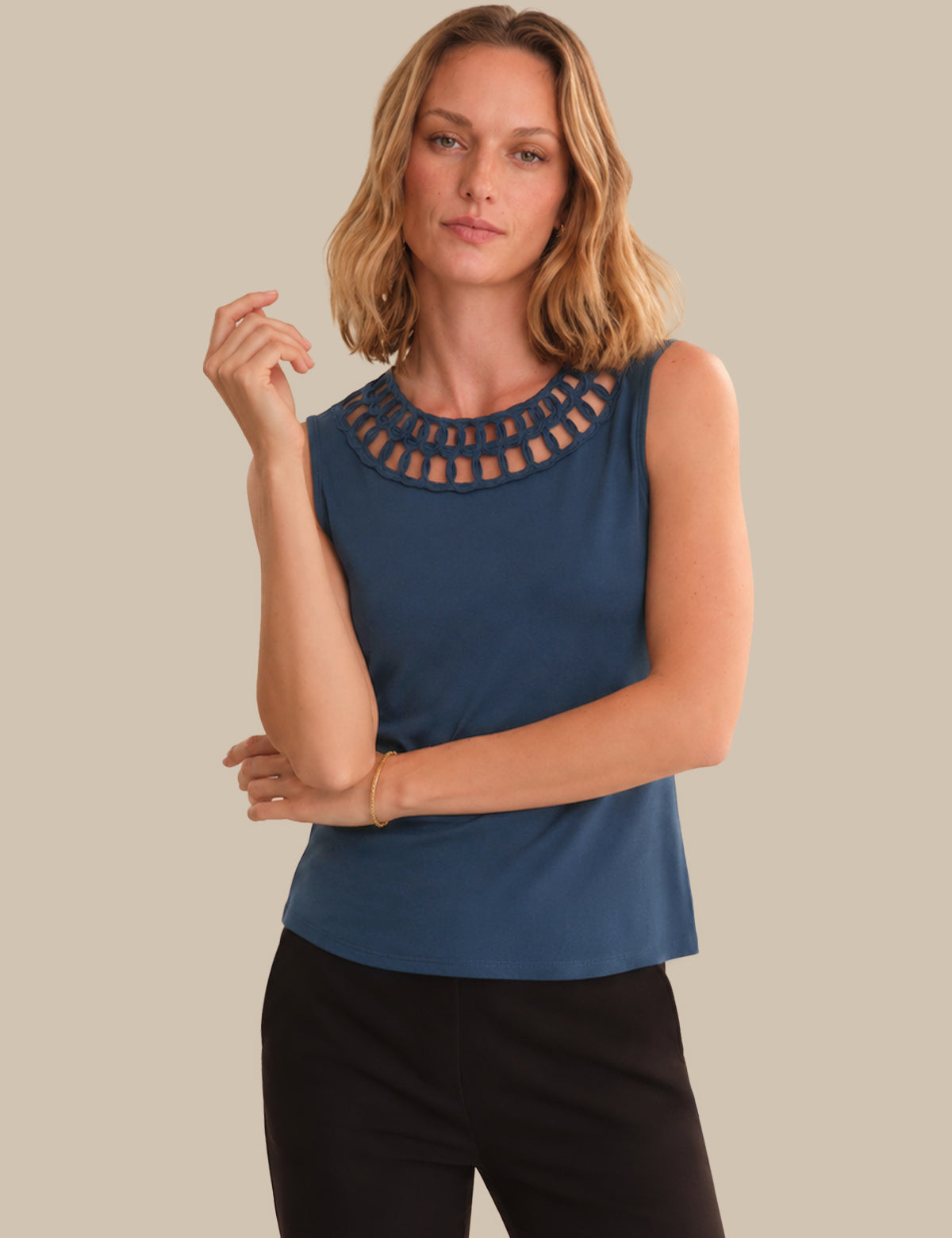 Woman wearing a blue sleeveless top with cut-out details on a beige background