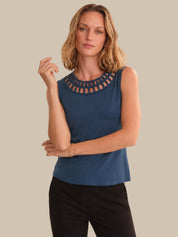 Woman wearing a blue sleeveless top with cut-out details on a beige background