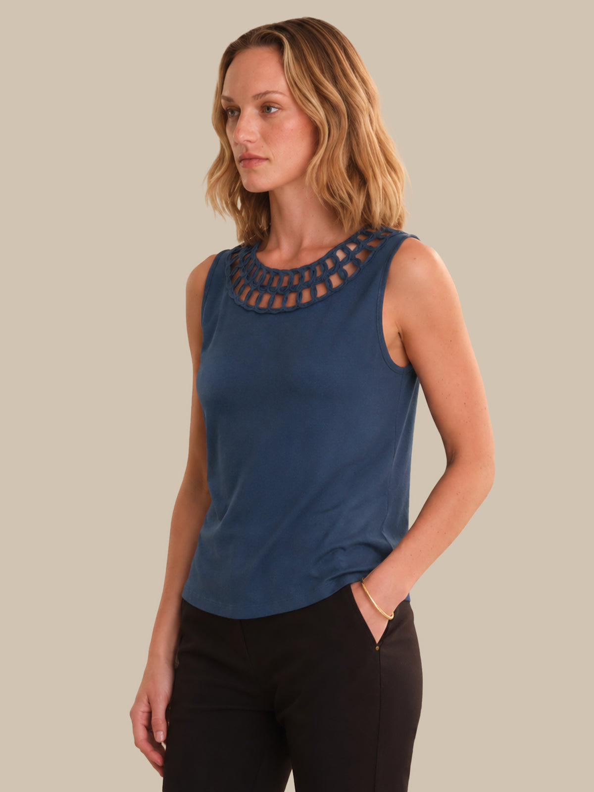 Woman wearing a blue sleeveless top with a textured neckline against a beige background