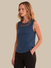 Woman wearing a blue sleeveless top with a textured neckline against a beige background