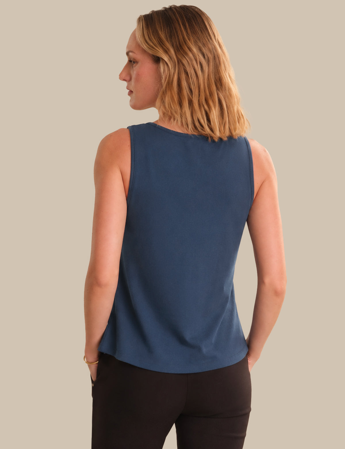 Woman wearing a blue sleeveless top against a beige background