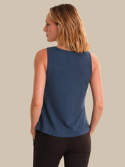 Woman wearing a blue sleeveless top against a beige background