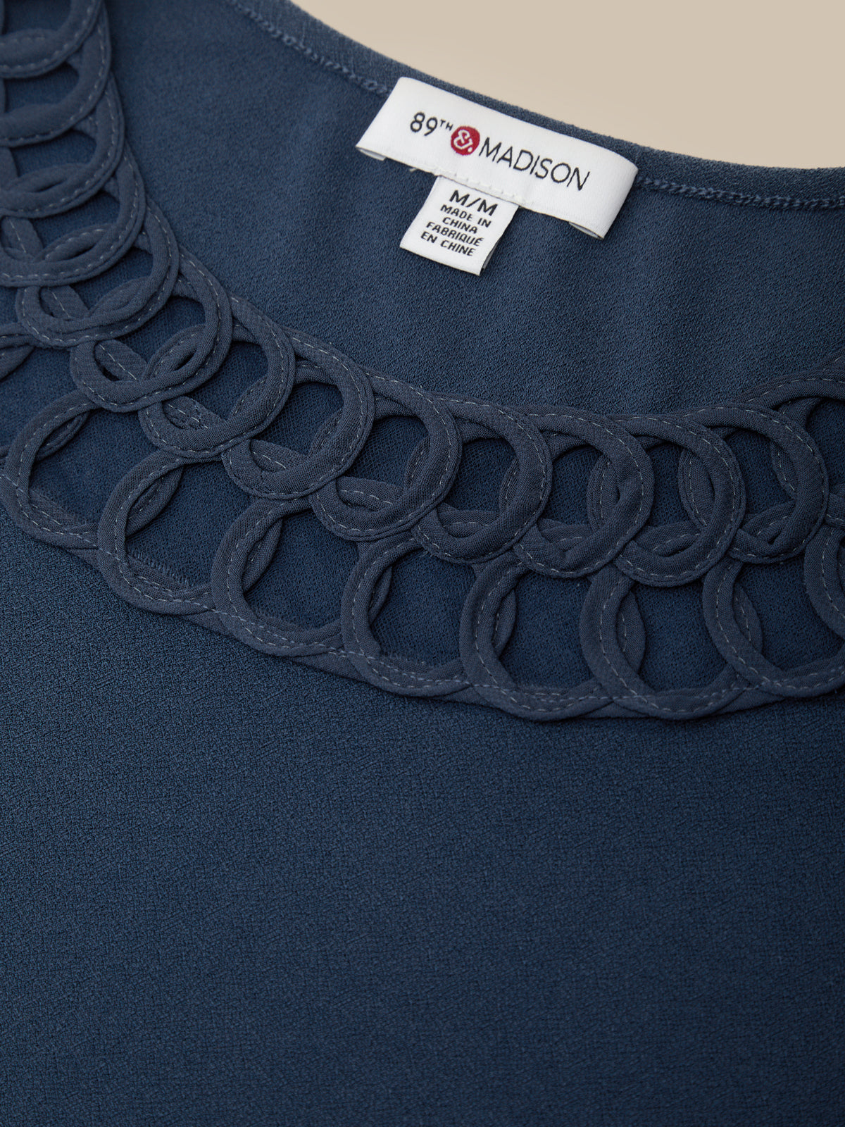 Navy blue garment with scalloped edge and 'Madison' label on a beige background