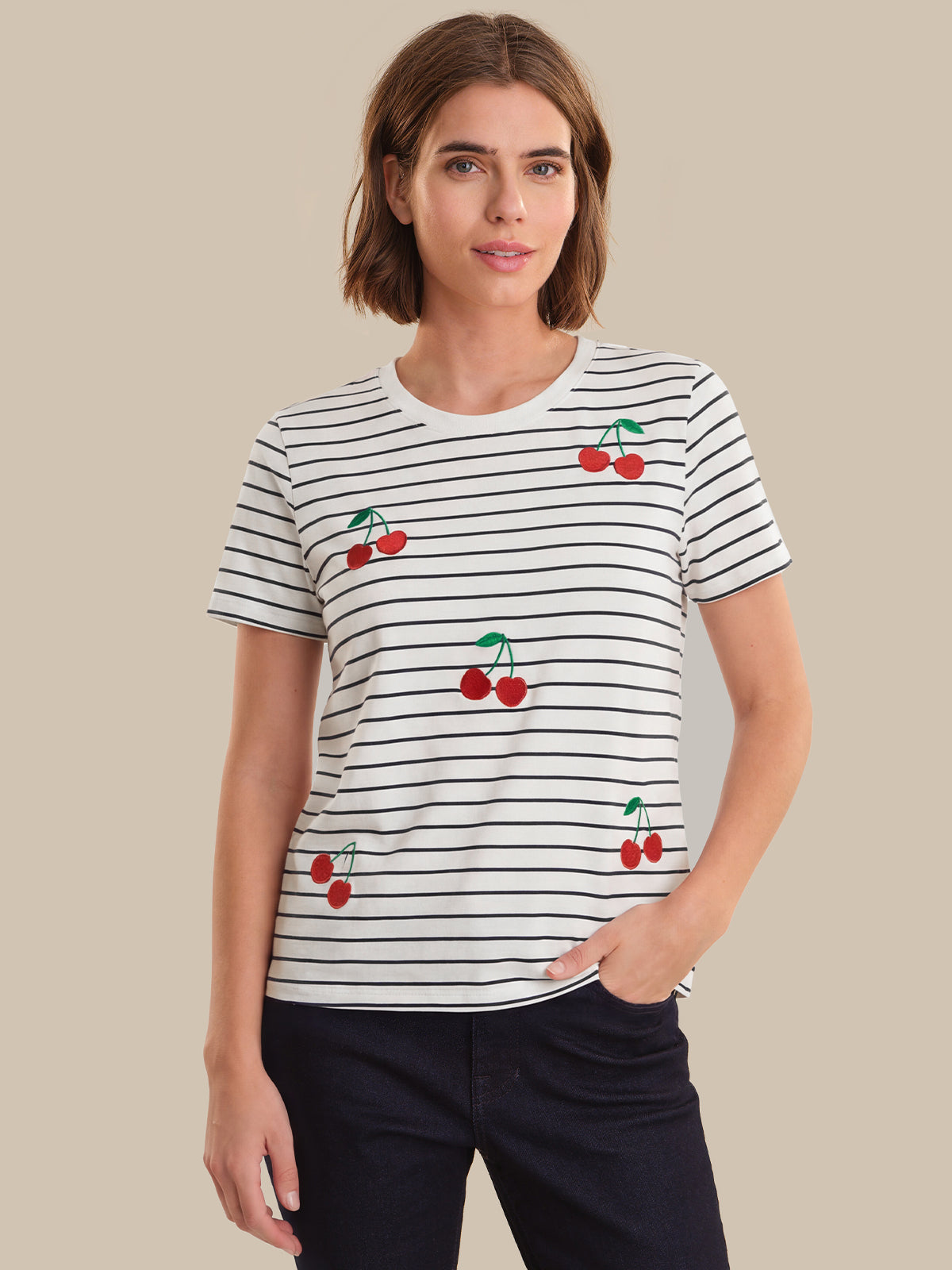Woman wearing a striped t-shirt with cherry designs on a beige background
