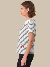 Woman wearing a striped t-shirt with cherry design on a beige background