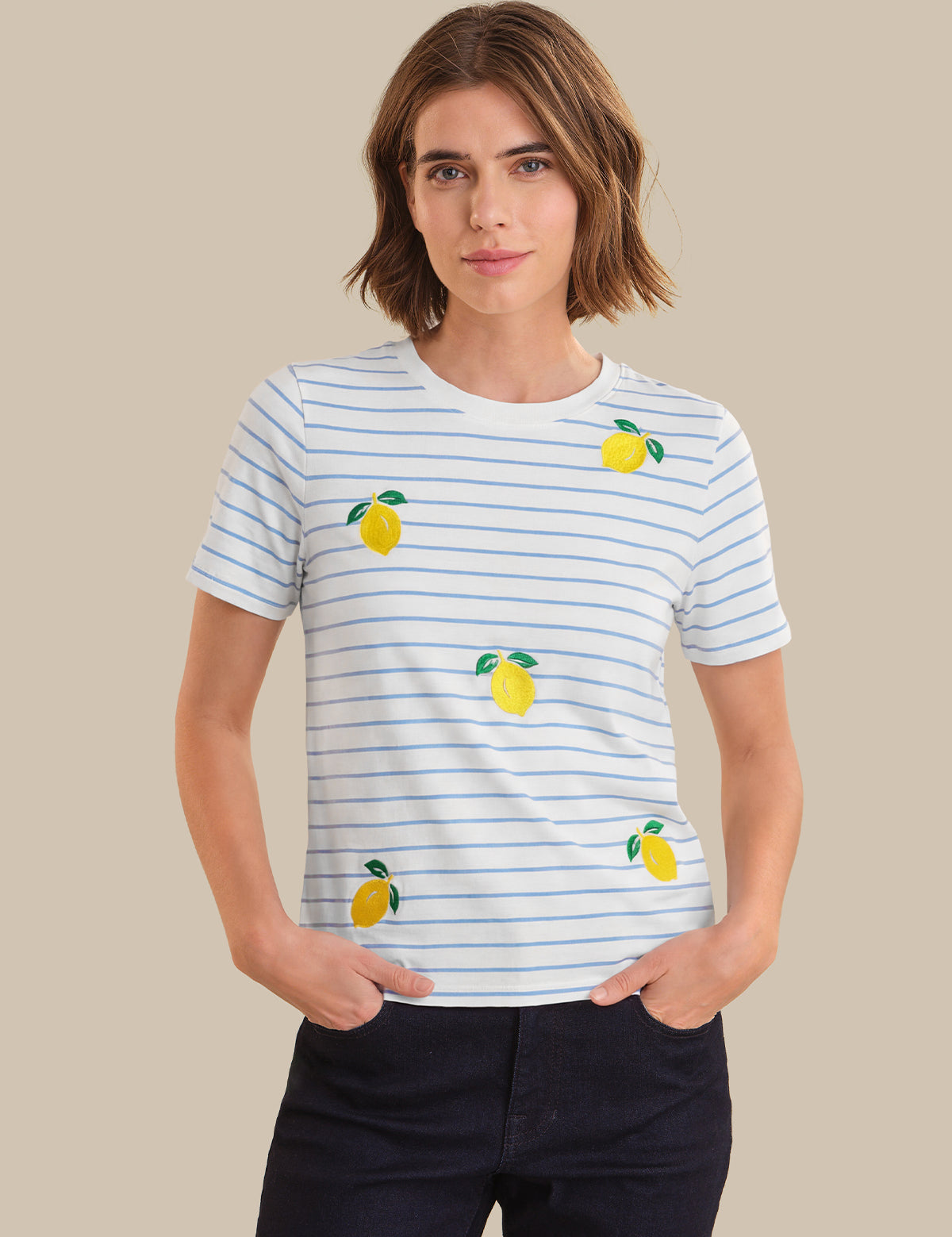 Person wearing a striped t-shirt with lemon designs on a beige background
