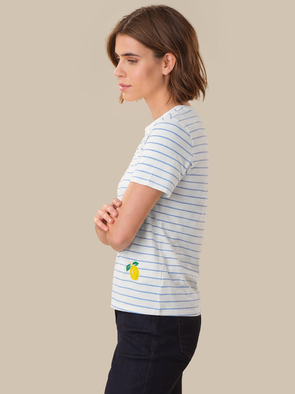 Woman wearing a striped t-shirt with a pineapple design on a beige background