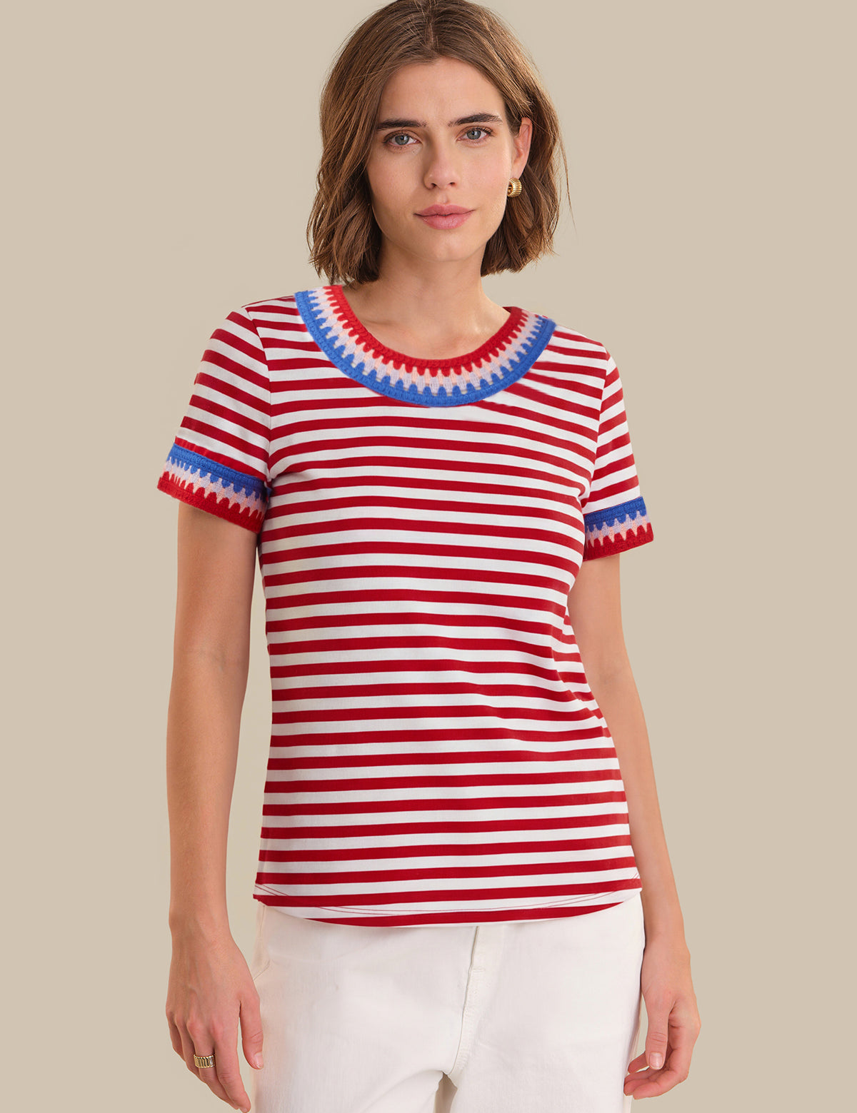 Woman wearing a red and white striped shirt with blue trim on a beige background