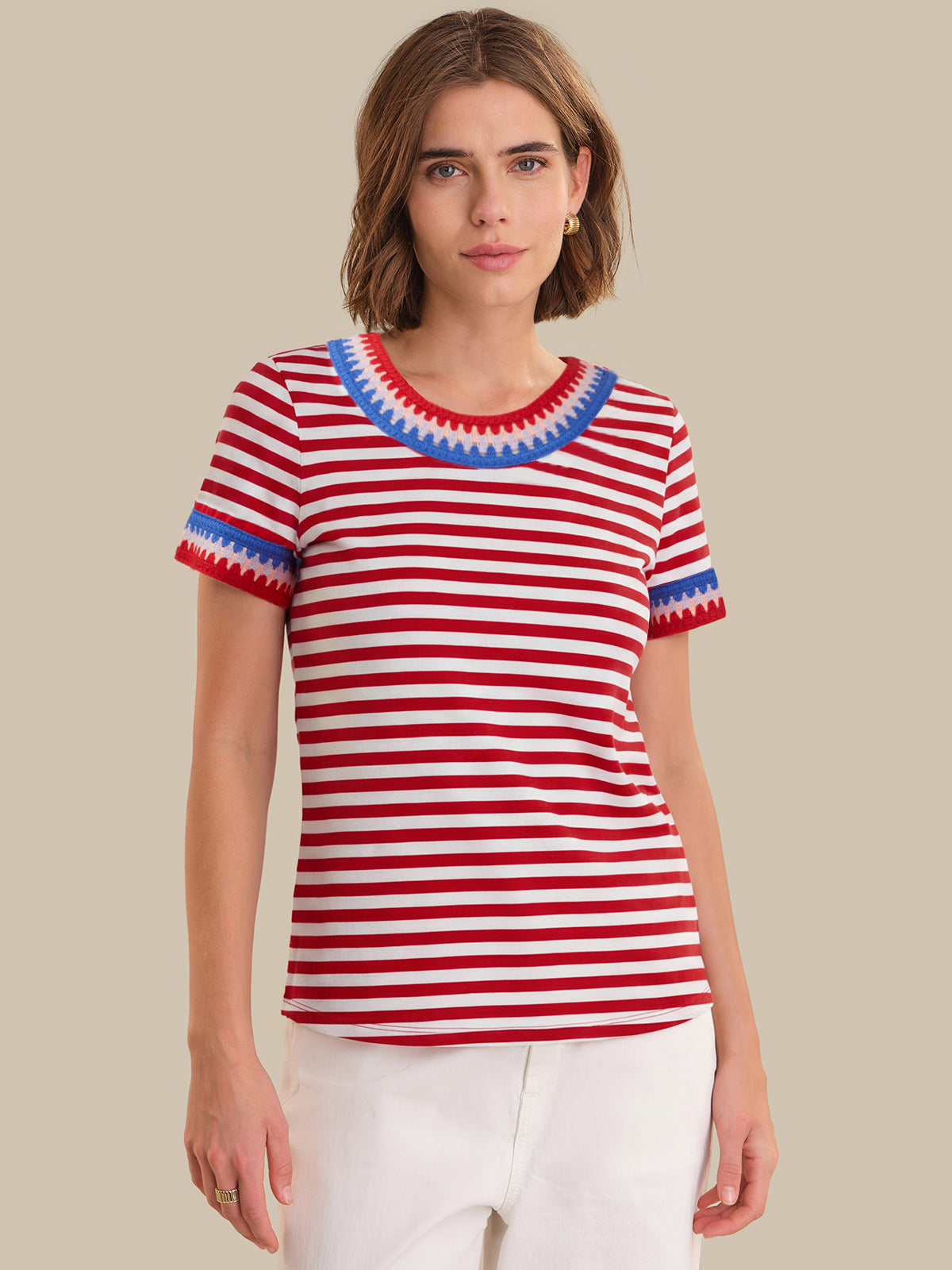 Woman wearing a red and white striped shirt with blue trim on a beige background