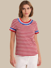 Woman wearing a red and white striped shirt with blue trim on a beige background