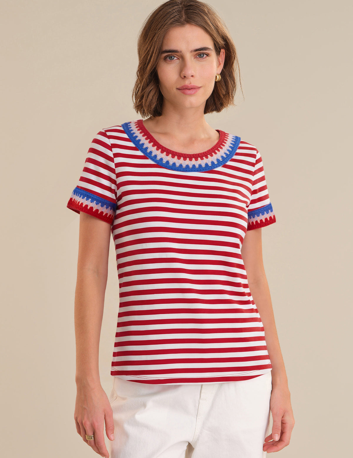 Woman wearing a red and white striped shirt with blue trim on a beige background