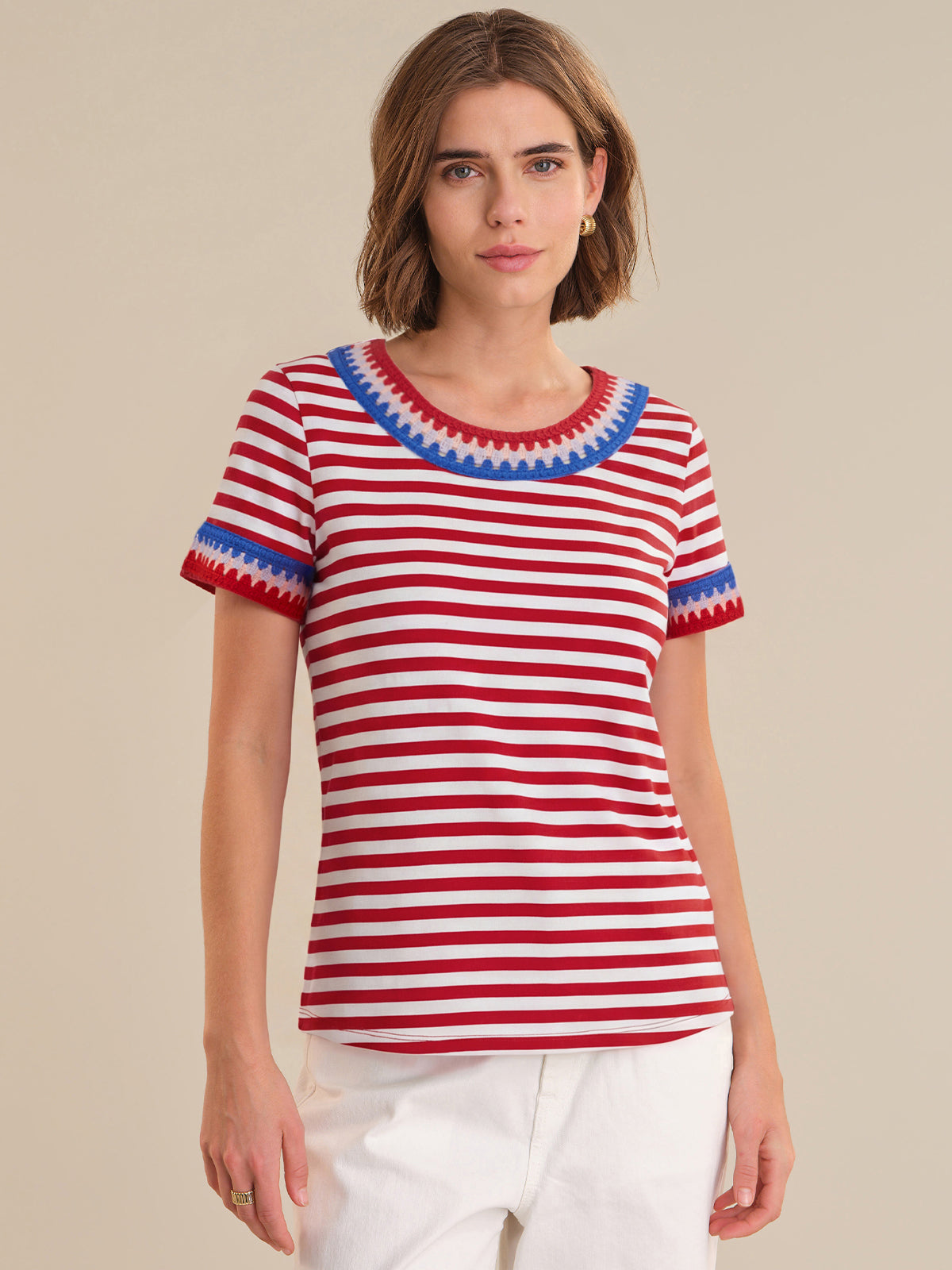 Woman wearing a red and white striped shirt with blue trim on a beige background