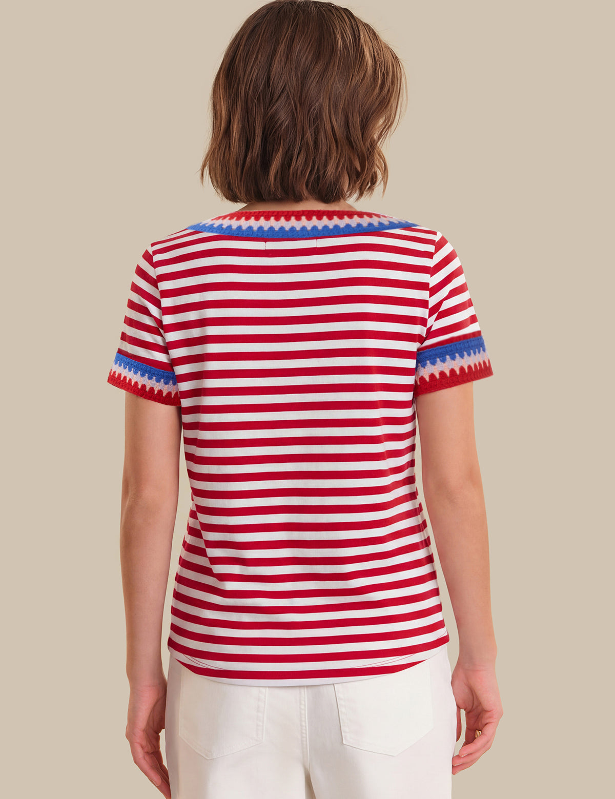 Person wearing a red and white striped shirt with blue trim on a beige background