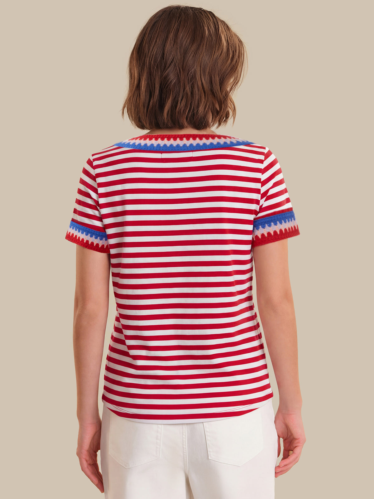 Person wearing a red and white striped shirt with blue trim on a beige background