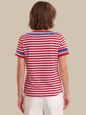 Person wearing a red and white striped shirt with blue trim on a beige background