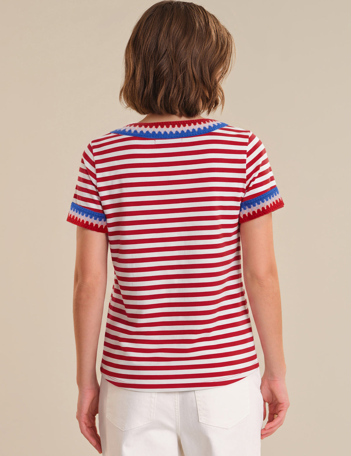 Person wearing a red and white striped shirt with blue trim on a beige background