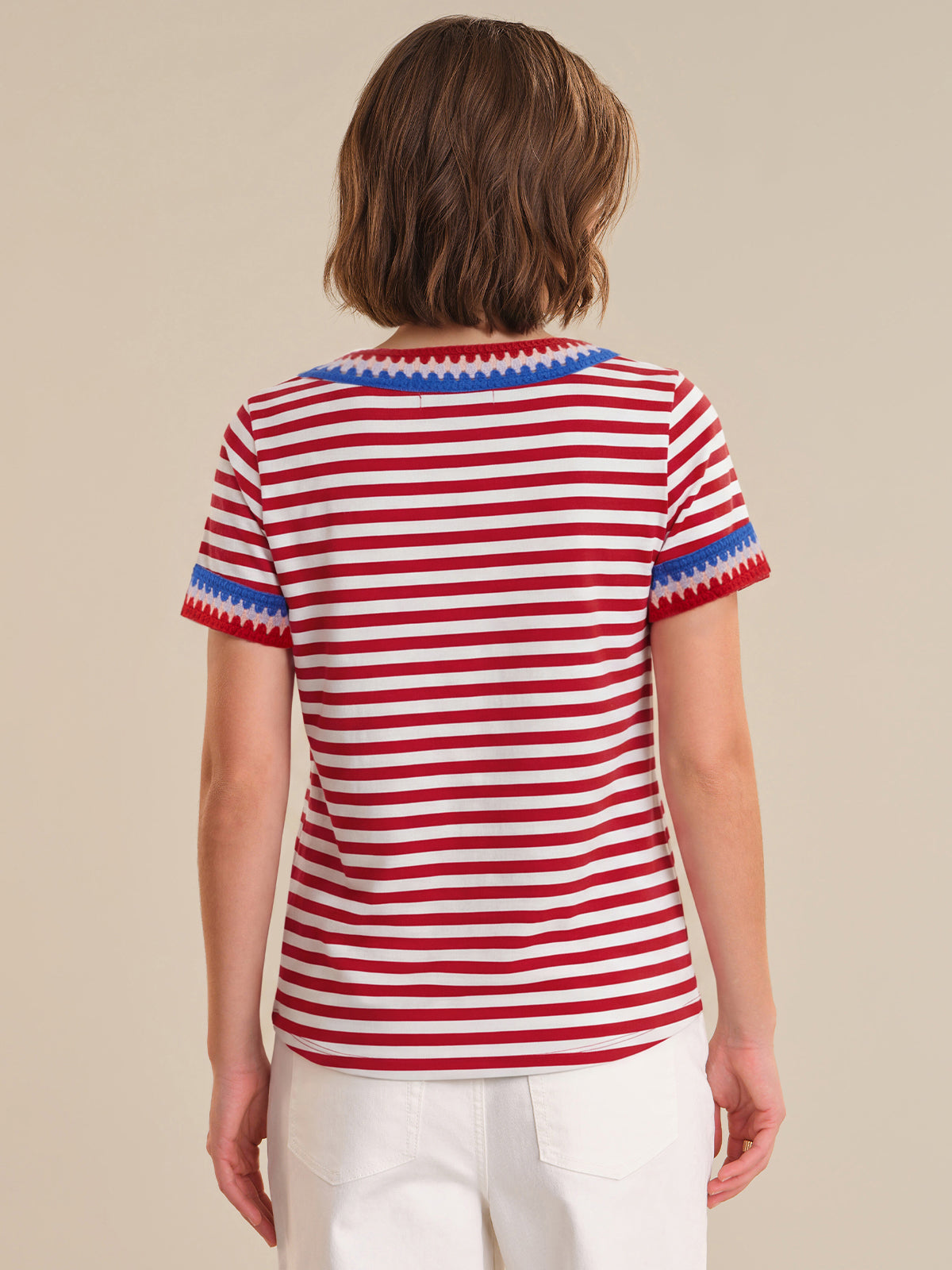 Person wearing a red and white striped shirt with blue trim on a beige background