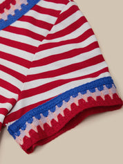 Red and white striped fabric with blue and pink border on a beige background