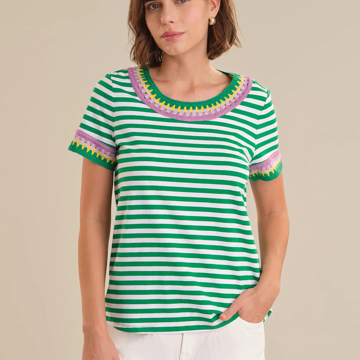 Woman wearing a green and white striped shirt with colorful trim on a beige background
