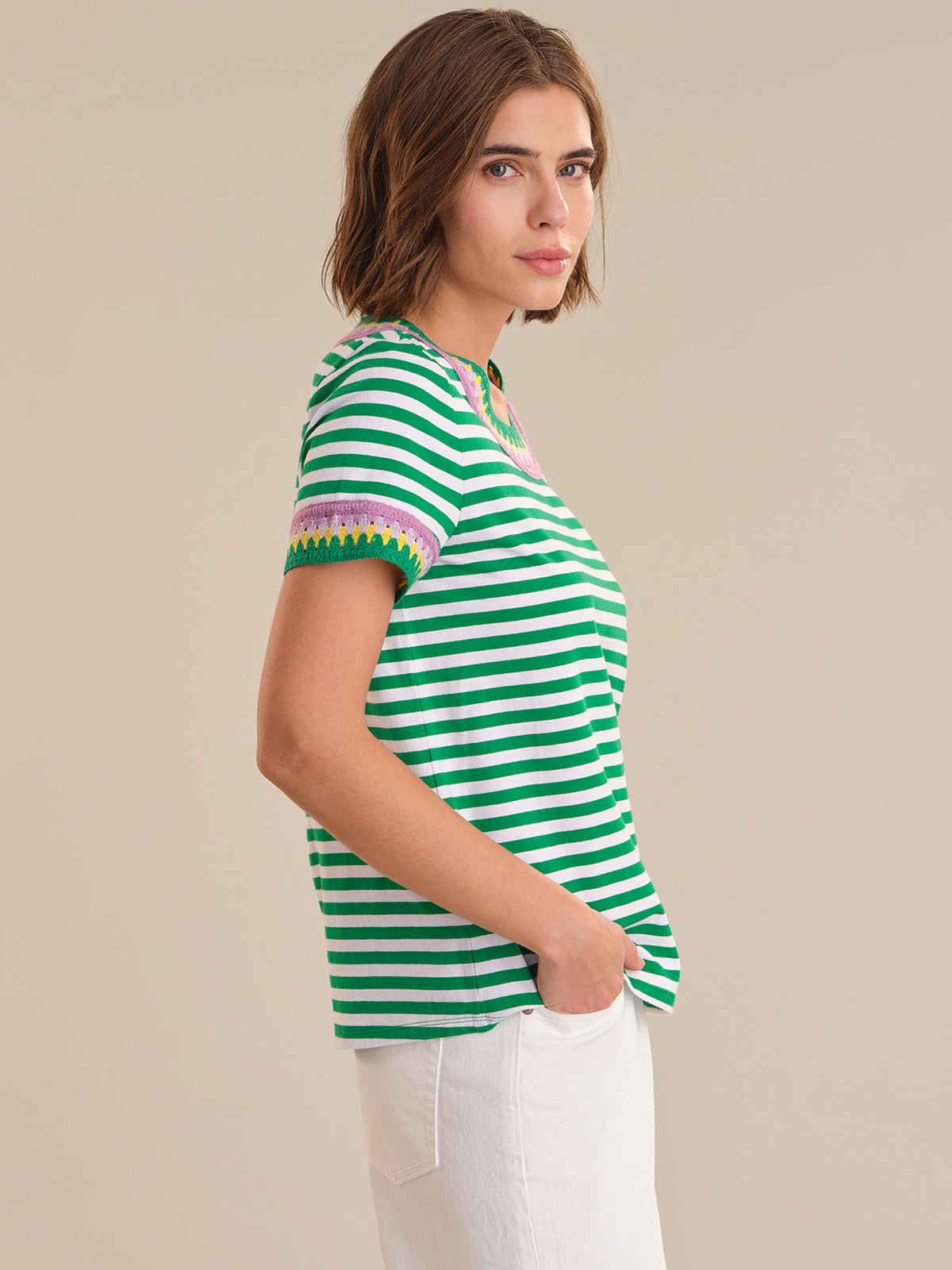 Woman wearing a green and white striped shirt with colorful trim on a beige background
