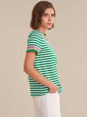 Woman wearing a green and white striped shirt with colorful trim on a beige background