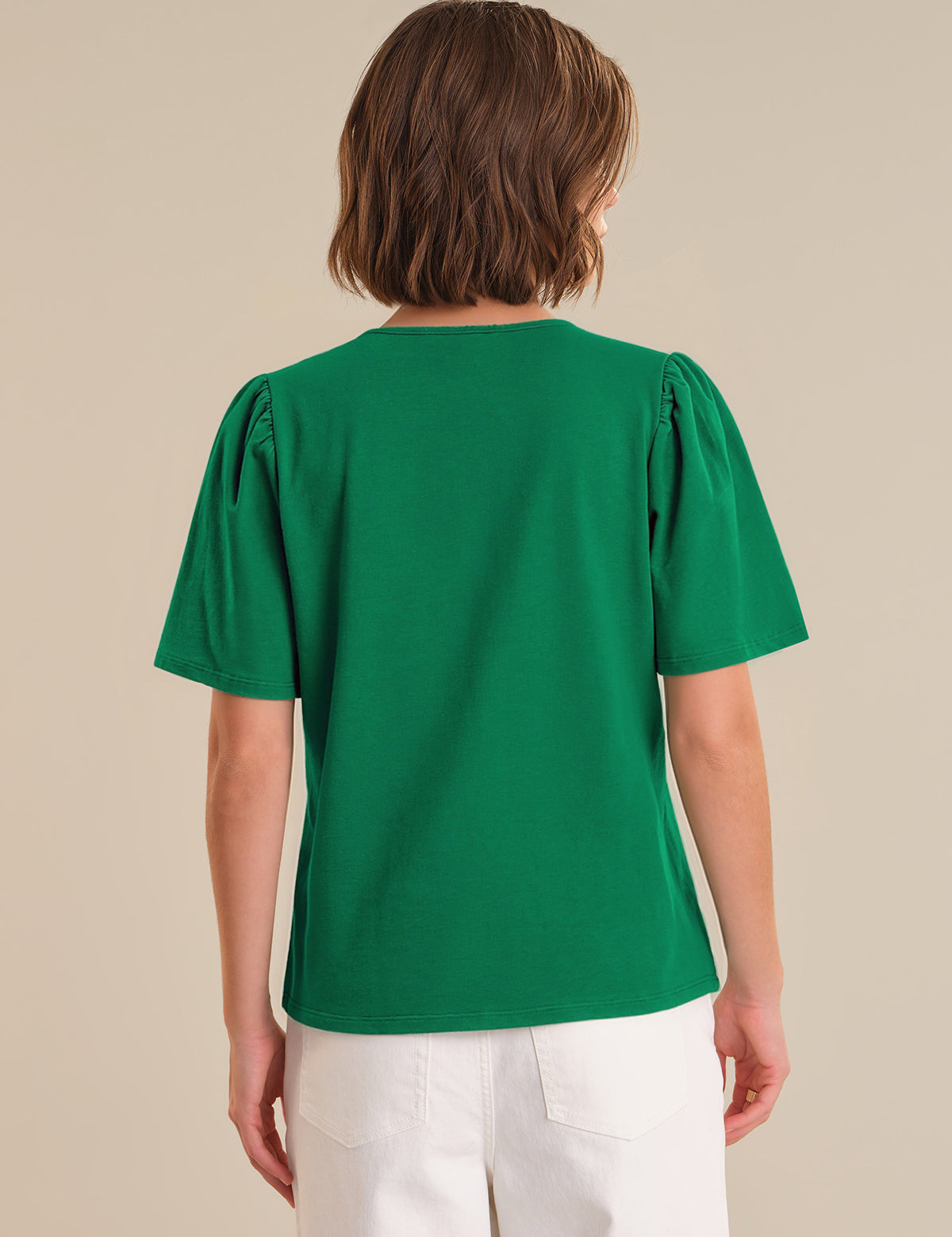 Person wearing a green blouse with puff sleeves on a beige background