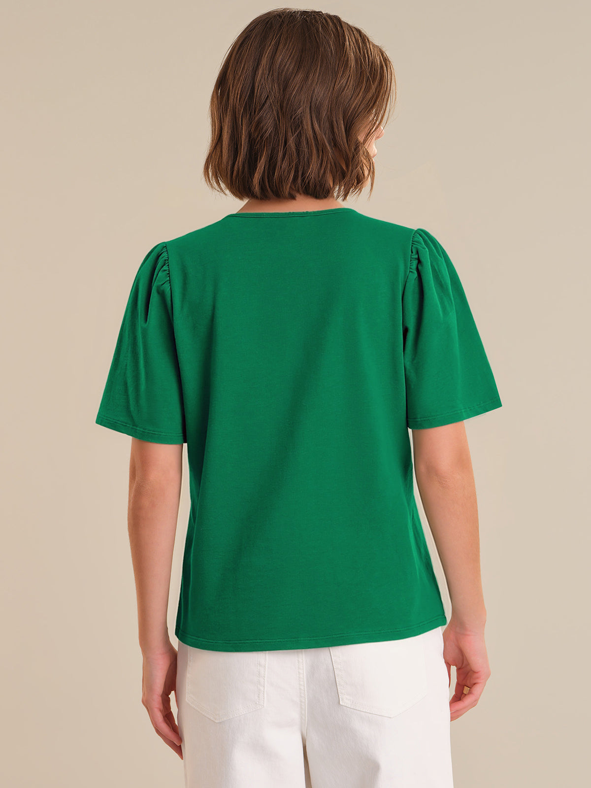 Person wearing a green blouse with puff sleeves on a beige background