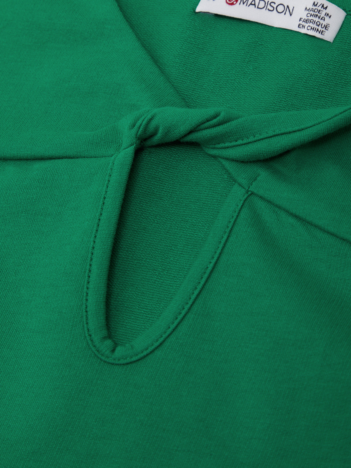 Close-up of a green garment with a brand label on a green background