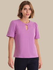 Woman wearing a purple blouse with a cut-out design on a beige background