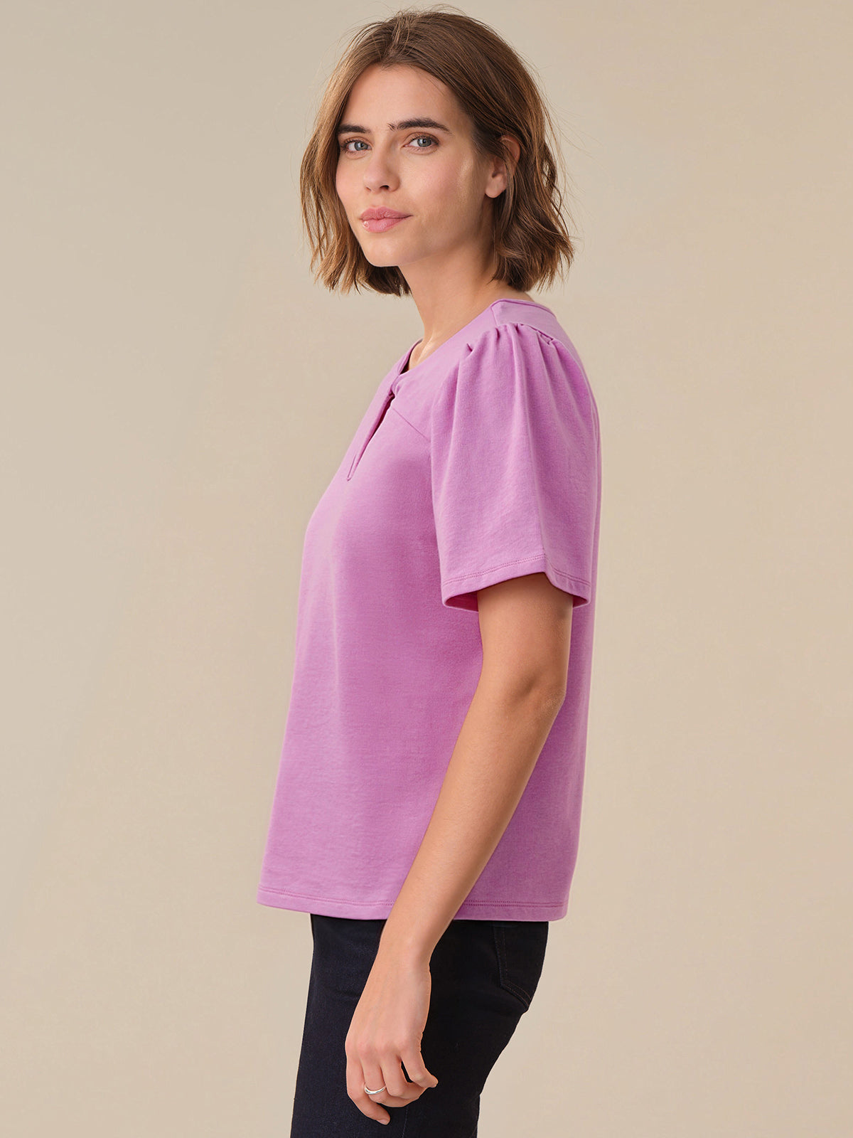 Woman wearing a purple blouse against a beige background