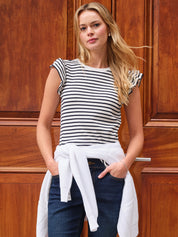 Woman wearing a black and white striped top with ruffled sleeves against a wooden background