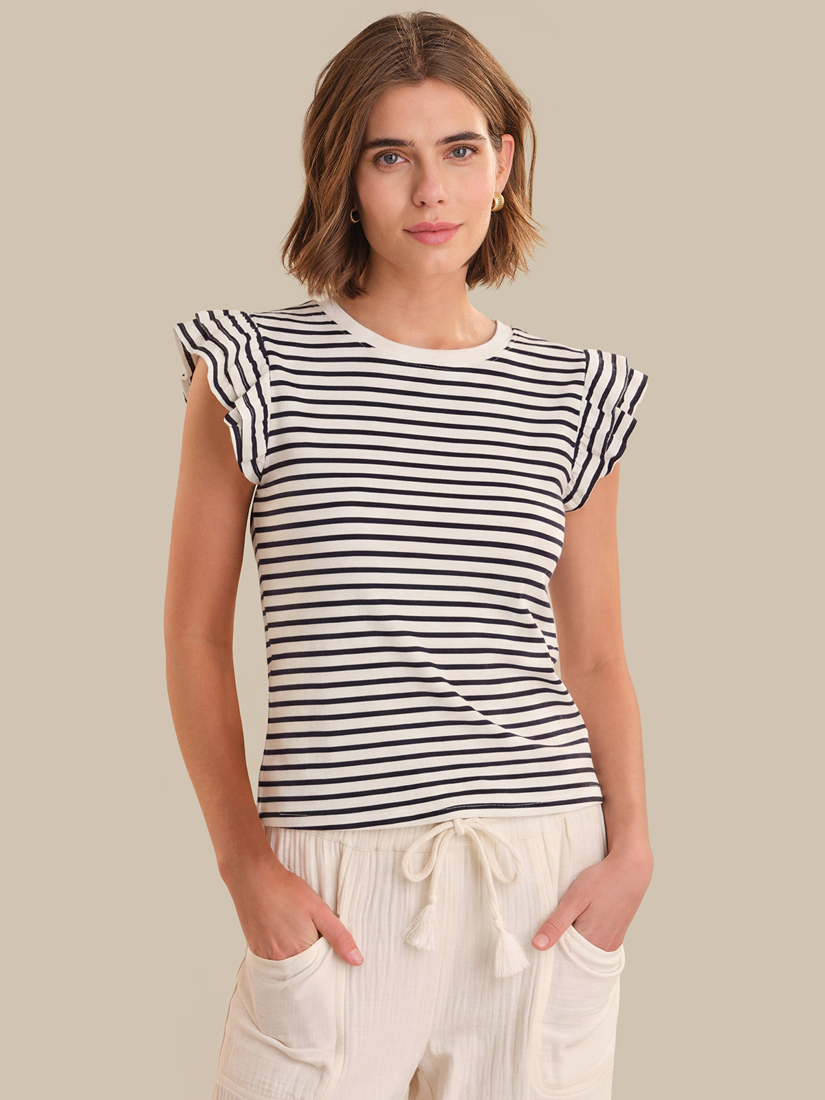 Woman wearing a black and white striped shirt against a beige background