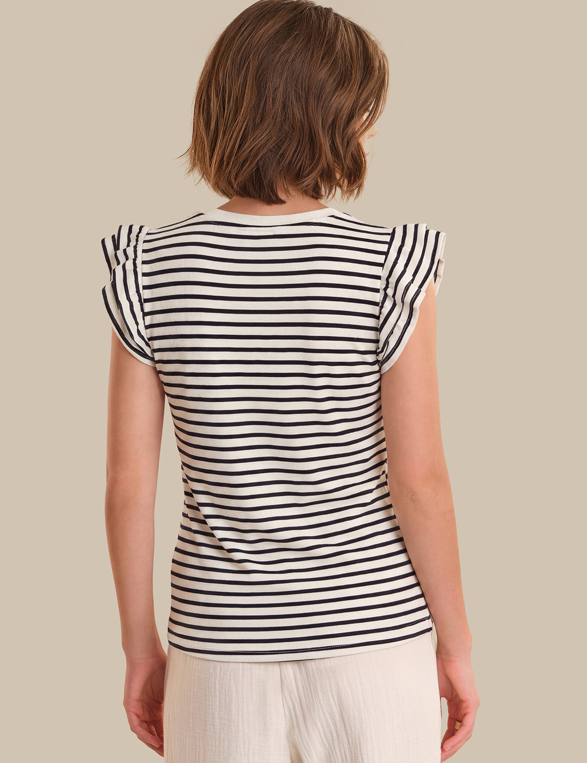 Woman wearing a black and white striped shirt against a beige background