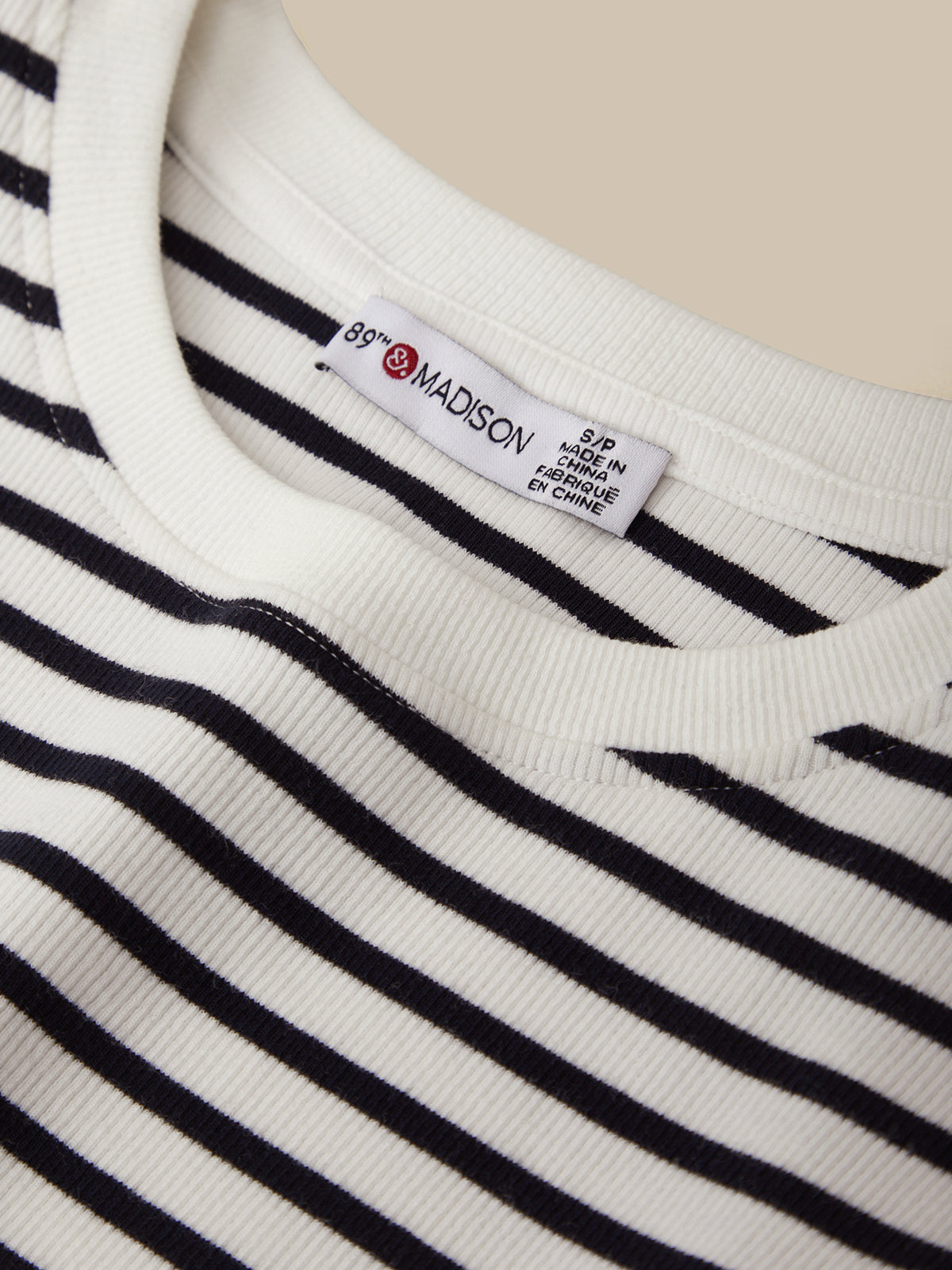 Close-up of a striped garment with a label on a beige background