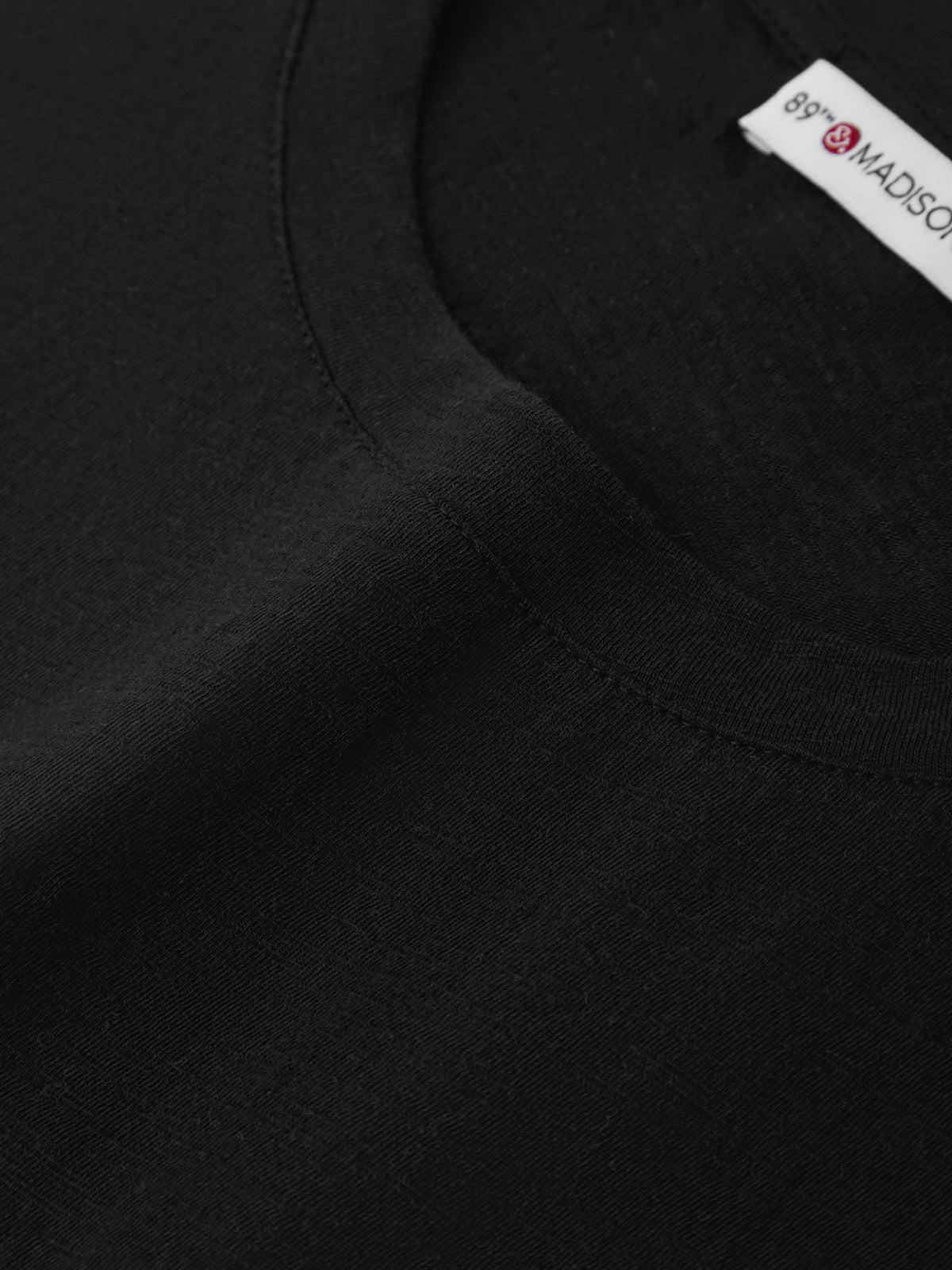 Close-up of a black garment with a brand label on a white background