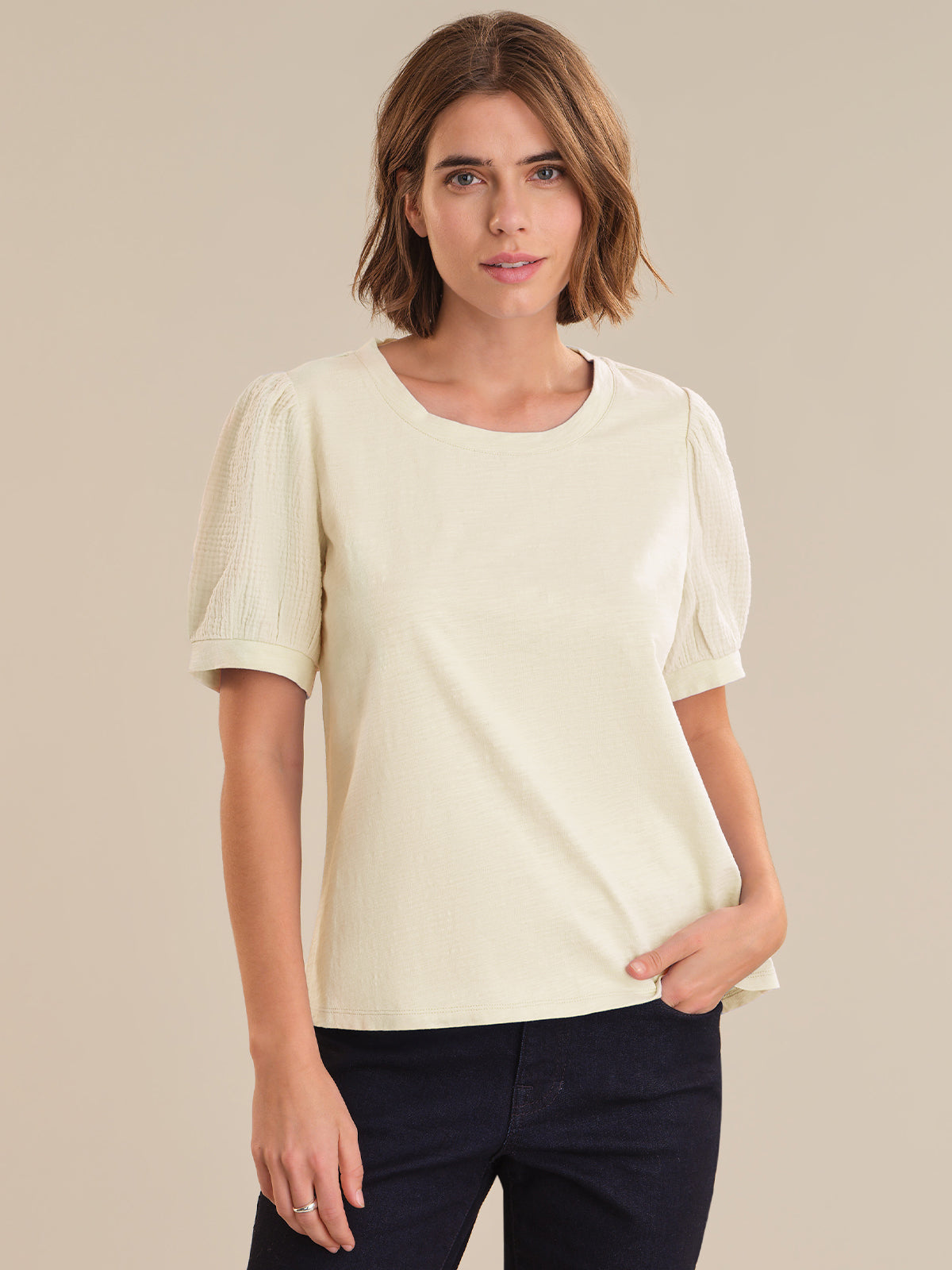 Woman wearing a light-colored blouse with short sleeves on a beige background