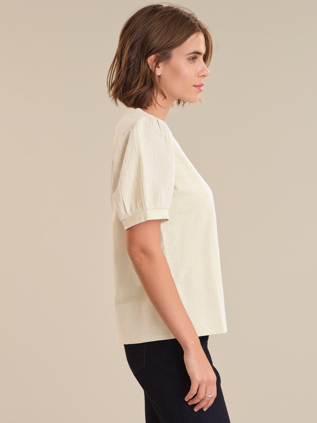 Woman wearing a light-colored blouse against a beige background