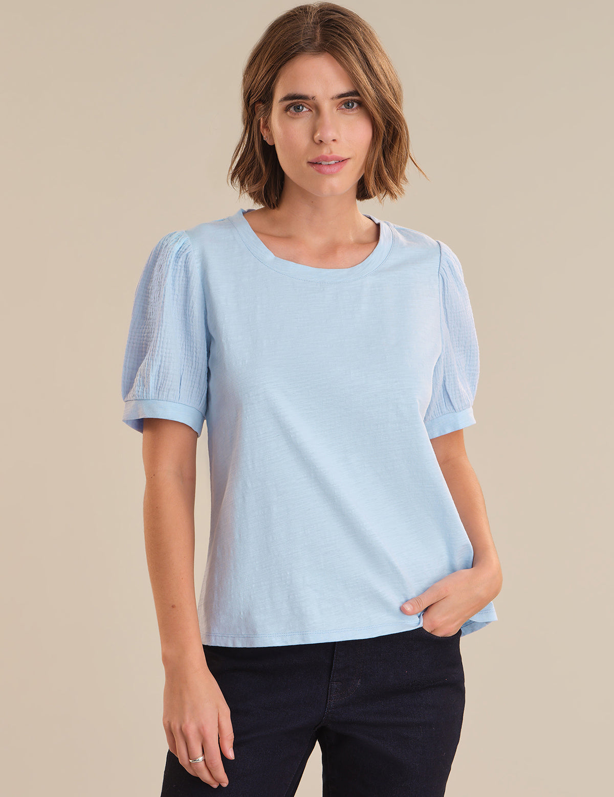 Woman wearing a light blue shirt against a beige background