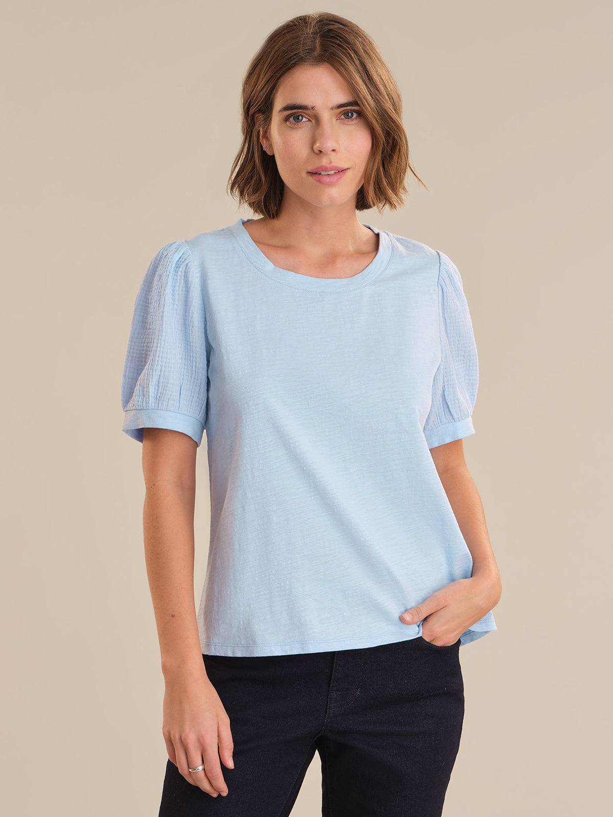 Woman wearing a light blue shirt against a beige background