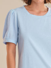 Light blue t-shirt worn by a person on a beige background