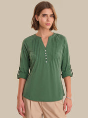 Woman wearing a green blouse with rolled-up sleeves on a beige background