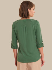 Woman wearing a green top with rolled-up sleeves on a beige background