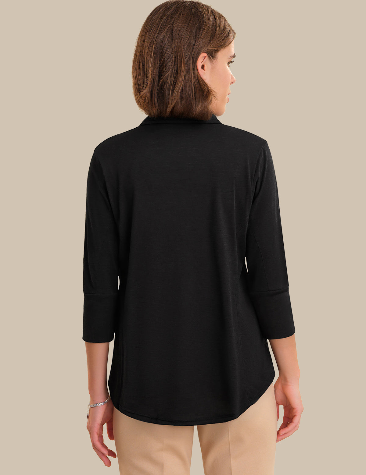 Woman wearing a black long-sleeve top against a beige background