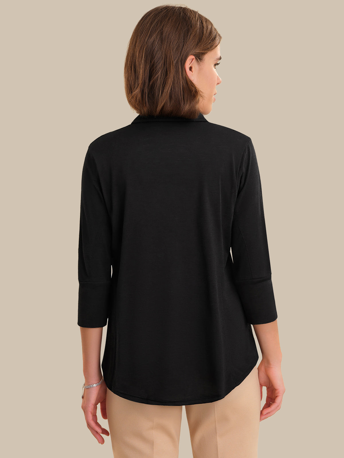 Woman wearing a black long-sleeve top against a beige background