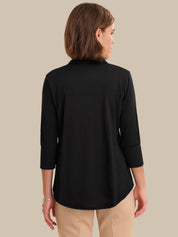 Woman wearing a black long-sleeve top against a beige background