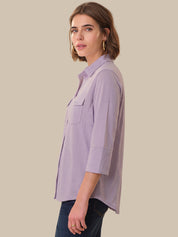 Woman wearing a light purple shirt against a beige background