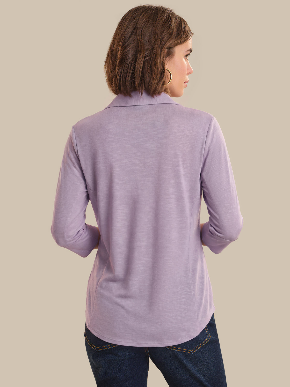 Woman wearing a purple long-sleeve shirt against a beige background