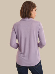 Woman wearing a purple long-sleeve shirt against a beige background