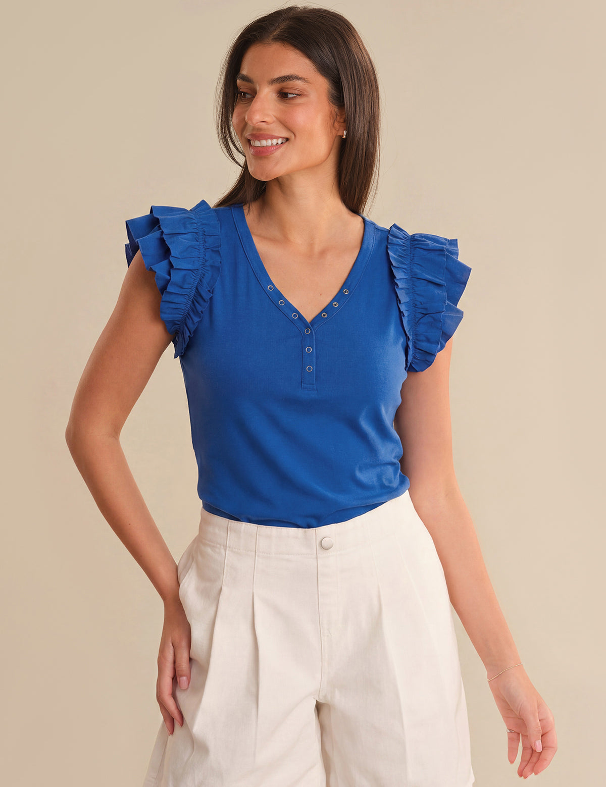 Woman wearing a blue top with ruffled sleeves on a beige background